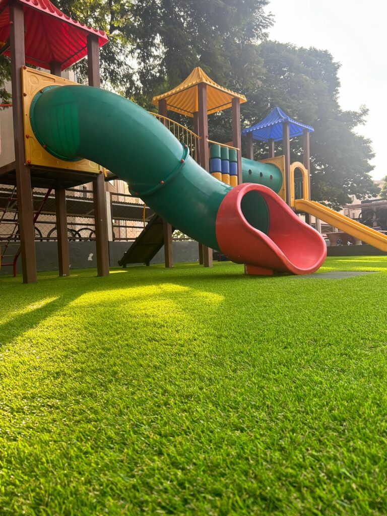 Imagem mostrando grama sintética instalado em parquinho de diversão voltado as crianças.